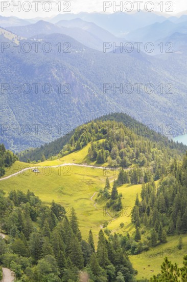 View over green hills and forests with mountain ranges in the background, Herzogstand summit, Walchensee, Schlehdorf, Germany