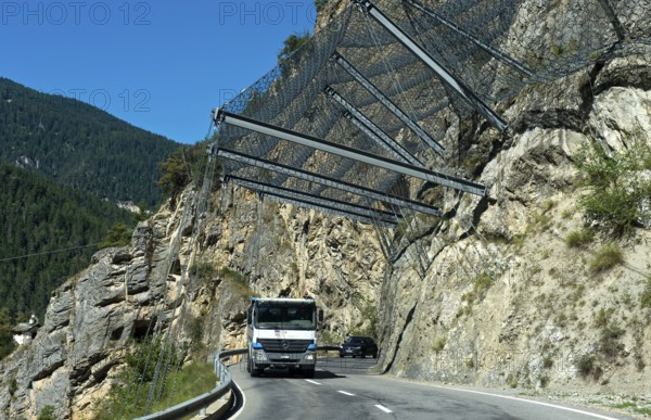 Motor vehicles travelling under safety nets on the rockfall-prone road Les Pontis, Val d'Anniviers, Valais, Switzerland