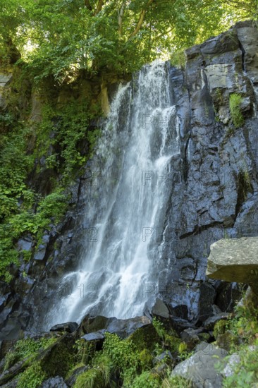 Vaucoux waterfall cascades gracefully over dark rocks, surrounded by lush greenery, Auvergne Volcanoes Regional Park, Puy de Dome., Auvergne-Rhone-Alpes, France