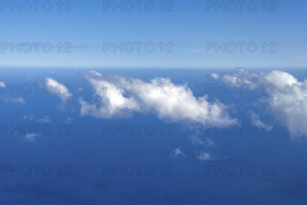 Aerial view from 11000 metres 36, 000 ft feet altitude on white cirrocumulus high cumulus clouds, in the background horizon and blue sky, below blue sea, International