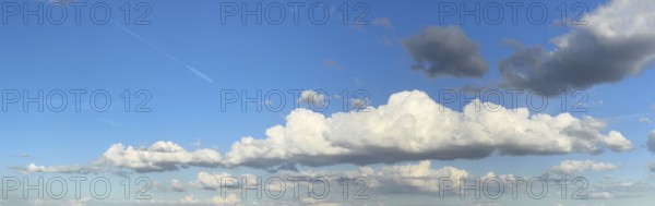 Panoramic photo of extended long wide stratocumulus white cloud cumulus clouds in front of bright blue sky, international