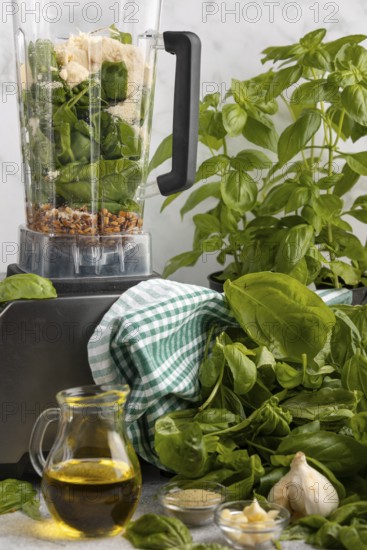 Blender with basil, parmesan and sunflower seeds alongside other ingredients for pesto