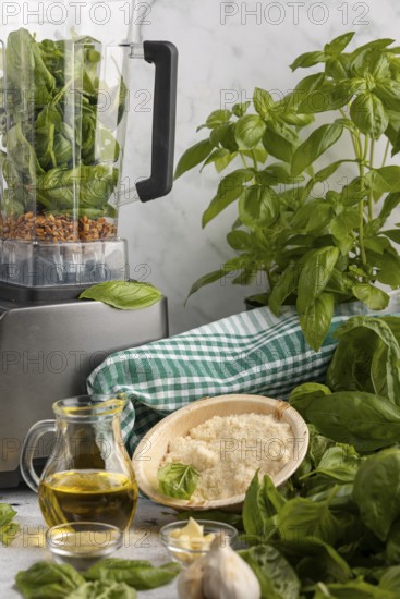 Blender with basil and sunflower seeds alongside other ingredients for pesto