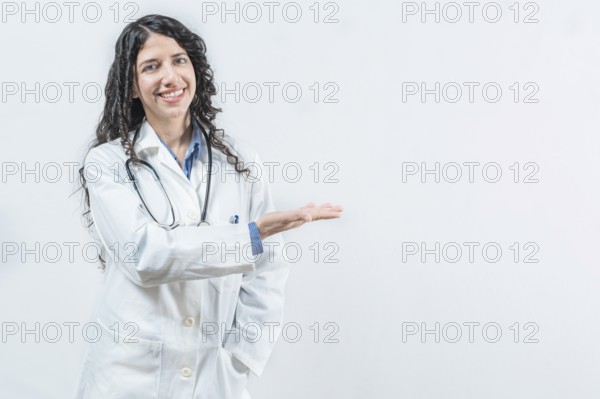 Smiling young female doctor showing empty space isolated. Female latin doctor showing a product isolated