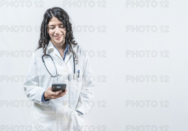 Smiling female doctor using smart phone isolated. Doctor holding phone, Concept of online medical services