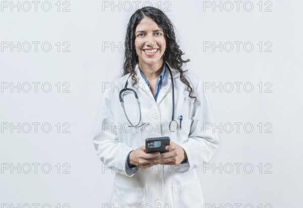 Young doctor holding phone, Concept of online medical services. Smiling female doctor using smart phone isolated