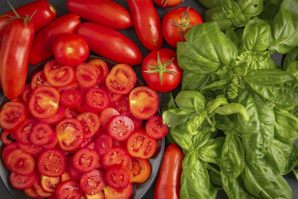Fresh sliced tomatoes and basil on a dark-coloured surface