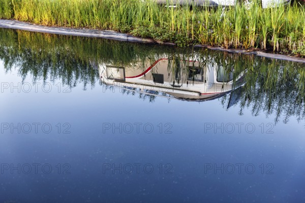 Motorhome reflected in swimming pond, camping site, Hodorf, Itzehoe, Schleswig-Holstein, Germany
