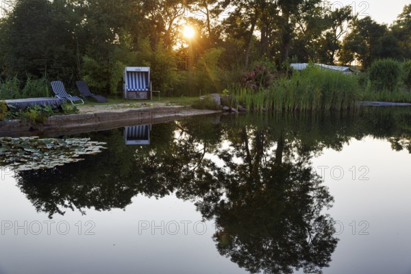 Idyllic swimming pond with beach chair and deckchairs, campsite, rays of sunshine in the evening, Itzehoe, Schleswig-Holstein, Germany