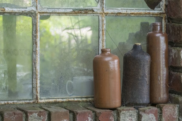 Three old earthenware bottles in front of a stable window, North Rhine-Westphalia, Germany
