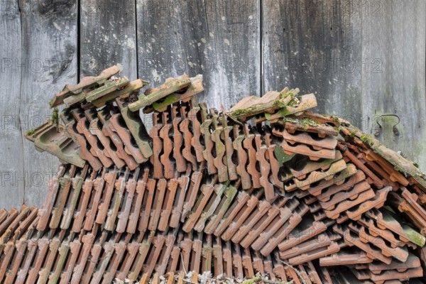 Old roof tiles stored in front of an old wooden barn, North Rhine-Westphalia, Germany