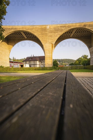 Massive stone bridge arches in the sunshine above a wooden bench, small town of Perle Nagold, Black Forest, Germany