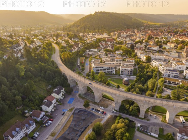 Aerial view of a town with viaduct and surrounding hills in warm sunlight, small town Perle Nagold, Black Forest, Germany