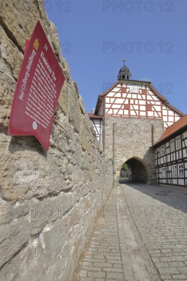 Historic lower gate with spire and clock and town wall, Tor tor, town gate, information board with text, inscription, Heldburg, Thuringia, Germany