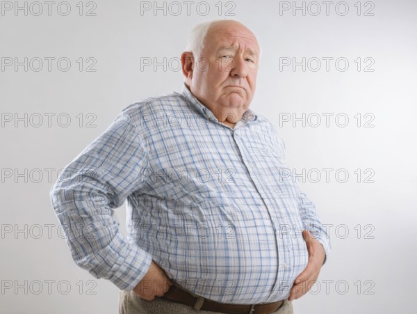 Elderly overweight man looks worried and holds his hands on his stomach, AI generated, AI generated