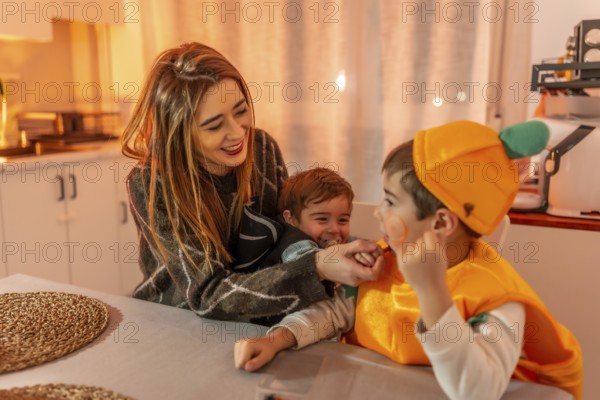 Smiling and playing together in the kitchen, a happy family enjoys halloween festivities while wearing colorful costumes and sharing joyful moments
