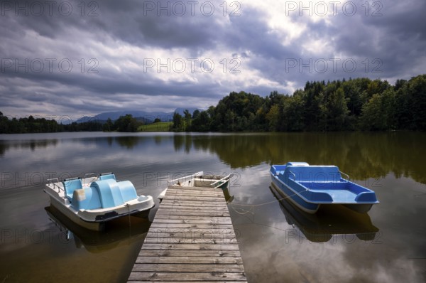 Rowing boat and pedal boats lying on a bathing jetty, jetty, wooden jetty, jetty, leads into a lake, bathing lake, Schwaltenweiher near Seeg, Allgäu Alps, East Allgäu, Allgäu, Swabia, Bavaria, Germany