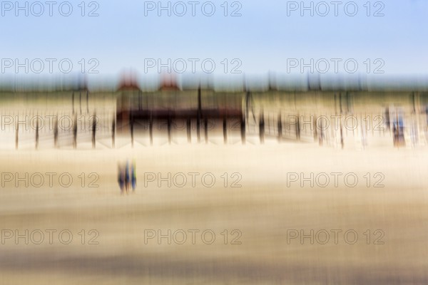 Three people on the North Sea beach, pile dwelling, stilt house, architecture, wipe effect, long exposure, Sankt Peter-Ording, Eiderstedt peninsula, Wadden Sea National Park, North Frisia, Schleswig-Holstein, Germany