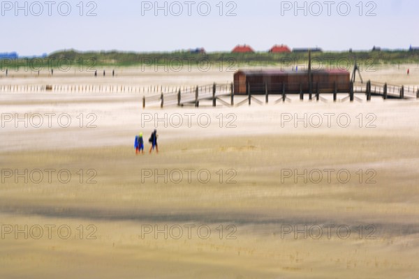 Strollers on the North Sea beach, pile dwelling, stilt house, wiping effect, long exposure, Sankt Peter-Ording, Eiderstedt peninsula, Wadden Sea National Park, North Frisia, Schleswig-Holstein, Germany