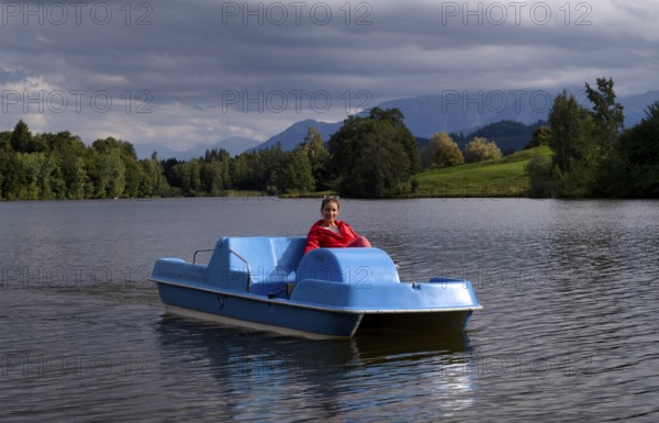 Woman, blonde, red jacket, riding pedal boat, bathing lake, lake, Schwaltenweiher near Seeg, Allgäu Alps, East Allgäu, Allgäu, Swabia, Bavaria, Germany