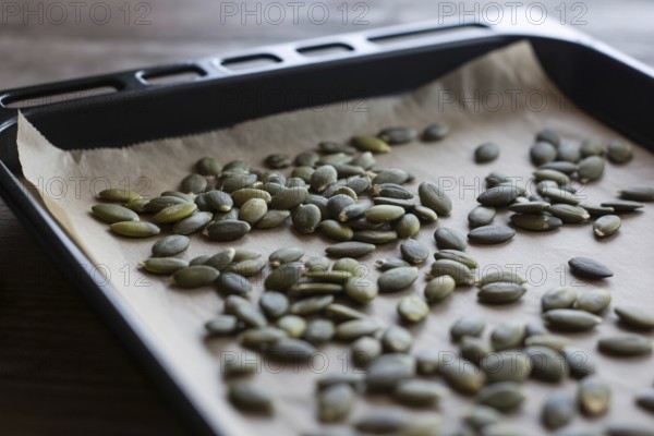 Pumpkin seeds spread out on baking tray ready for roasting. Healthy snack preparation with natural texture and detail.. Generative ai, AI generated