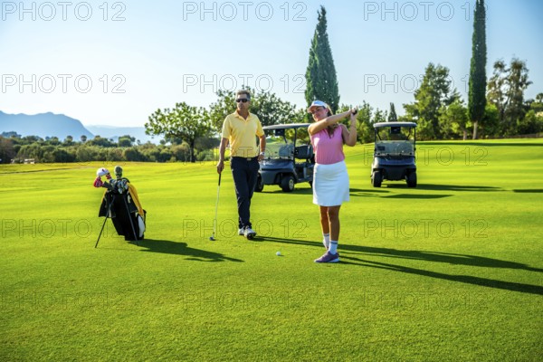 Couple enjoying a sunny day on the golf course, playing together and relishing their leisure time in the vibrant outdoor setting