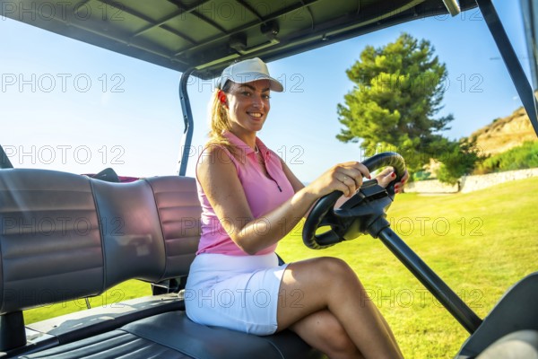 Female golfer driving golf cart on a sunny day at the golf course, enjoying the beautiful scenery