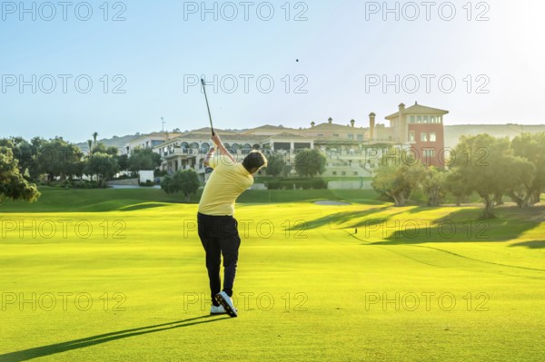 Golfer hitting a shot on a beautiful, sunny golf course with a luxury resort in the background
