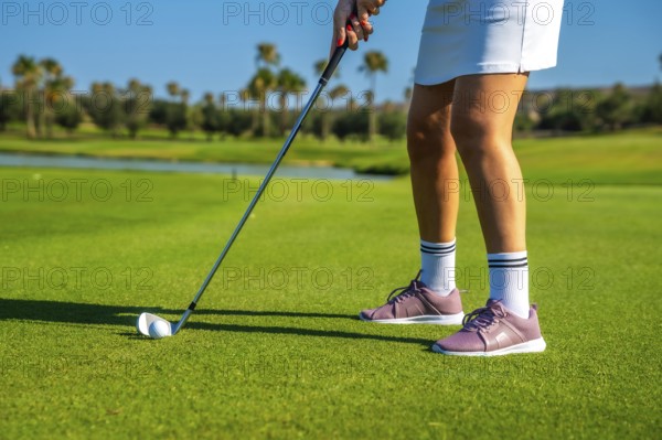 Female golfer concentrating intensely while hitting the golf ball on a bright, sunny day at the lush green golf course