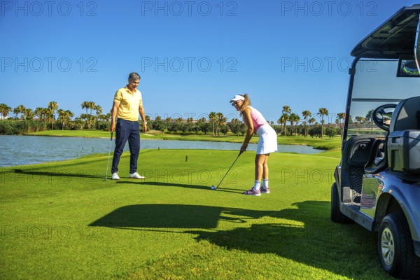 Couple playing golf on a beautiful sunny day, enjoying the sport and the stunning scenery surrounding the course
