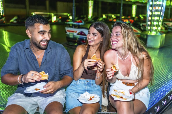 Happy friends enjoying burgers and pizza at amusement park, having fun together on a summer night out