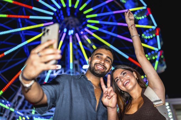Joyful friends capturing a selfie with a vibrant ferris wheel in the background, celebrating a fun night at the carnival