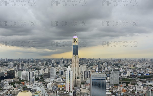 Bangkok cityscape featuring baiyoke tower ii standing tall amidst other buildings under a dramatic cloudy sky, showcasing urban density and architectural prominence