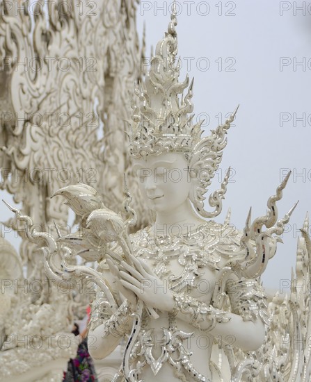White sculpture holding lotus flowers at the famous wat rong khun, also known as the white temple, in chiang rai, thailand, showcasing intricate details and spiritual symbolism