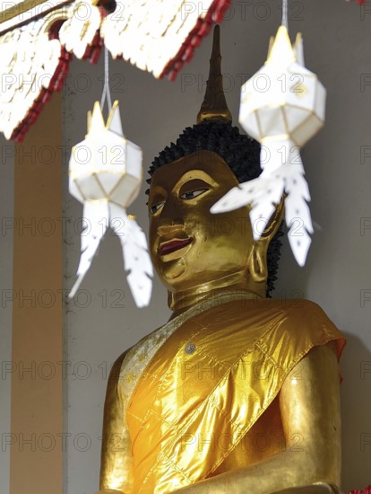 Majestic golden buddha statue wearing a yellow robe, serene and peaceful, inside a traditional thai temple, adorned with ornate decorations