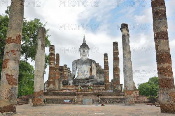 Serene buddha statue sits majestically amidst ancient ruins, showcasing the rich spiritual and architectural heritage of sukhothai