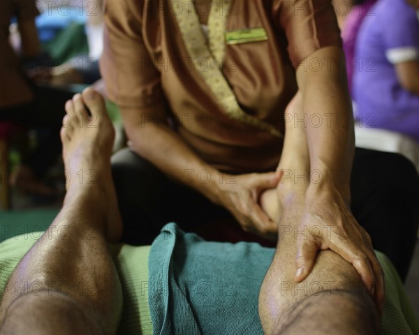 Close up of a thai masseuse performing a relaxing leg massage on a tourist, showcasing the traditional healing practices of thailand