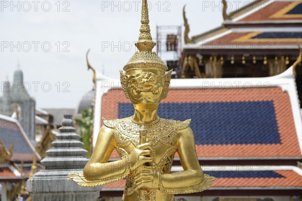 Majestic golden kinnara statue stands guard at wat phra kaew, the temple of the emerald buddha, a prominent landmark in bangkok, thailand