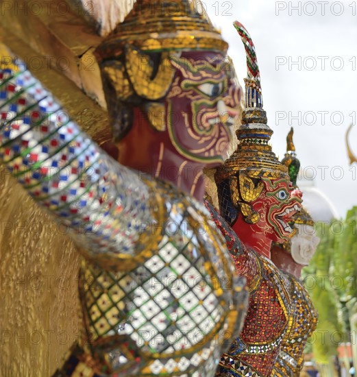 Giant colorful mosaic statues are guarding a thai temple, showcasing the intricate artistry and spiritual significance of these figures in thai culture