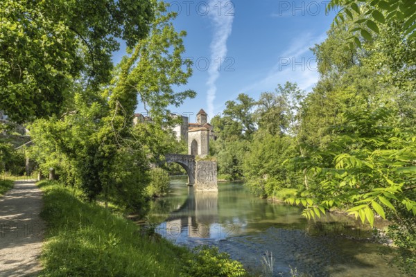 Scenic view of the historic stone bridge spanning the gave d'oloron river, with lush green foliage and a clear blue sky in sauveterre de bearn, france