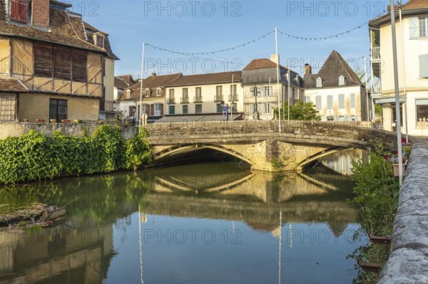 Scenic view of the old stone bridge reflecting in the calm river during a sunny morning in the charming village of salies de bearn, france