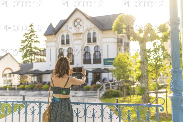 Young woman taking a photo of a beautiful building in salies de bearn, france, during her summer vacation