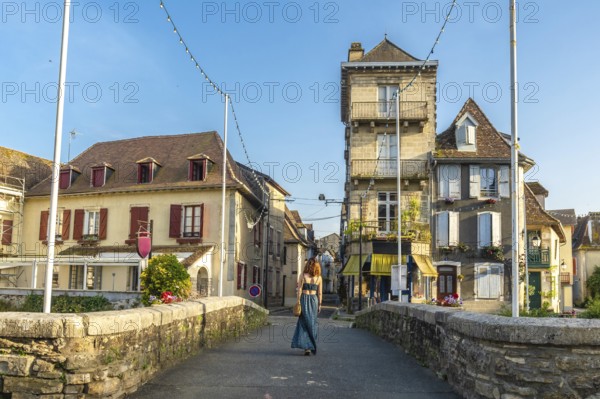 Young woman walking across a bridge in the historic village of salies de bearn, france, enjoying the charming atmosphere and traditional architecture