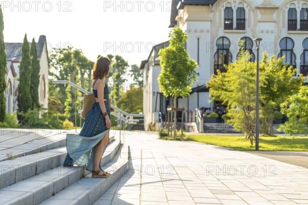 Young woman descending stairs in salies de bearn, a picturesque village in the pyrenees atlantiques region of france, enjoying a leisurely stroll during her summer vacation
