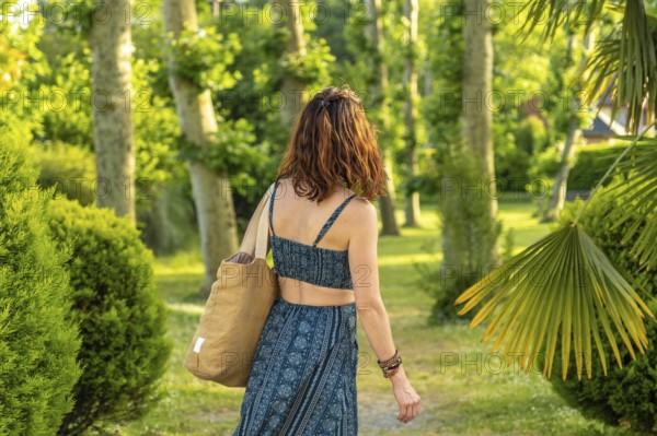 Tourist walking through a picturesque park in salies de bearn, france, carrying a tote bag and soaking up the summer vacation atmosphere