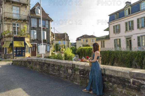 Tourist holding flowers and enjoying the view of a canal in the charming village of salies de bearn, france, during summer vacation