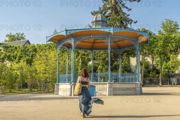Tourist walking away from a bandstand in salies de bearn, a french village famous for its salt production, during a sunny summer day