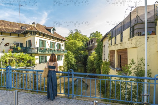 Tourist admiring the picturesque canal and traditional houses in the charming village of salies de bearn, a popular destination in the french pyrenees