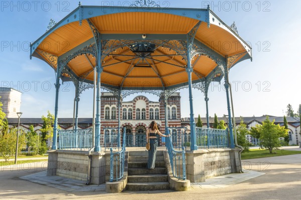 Tourist ascending stairs of a gazebo in a park in salies de bearn, france, enjoying a summer vacation day