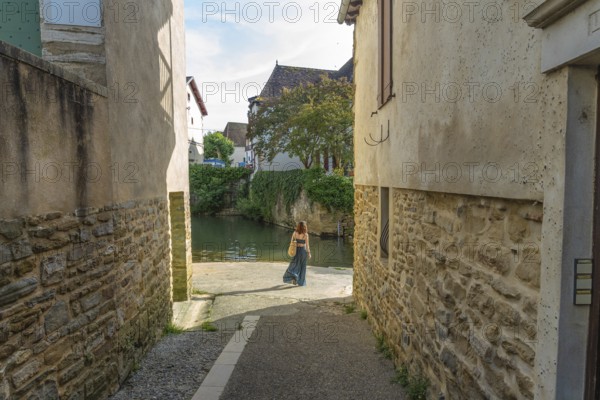 Tourist walking by the gave de salies river in the charming medieval village of salies de bearn, a popular tourist destination in the pyrenees atlantiques region of france